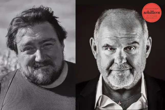 Der Mann mit dunklem Hemd und Bart, lächelnd, in Schwarz-Weiß.